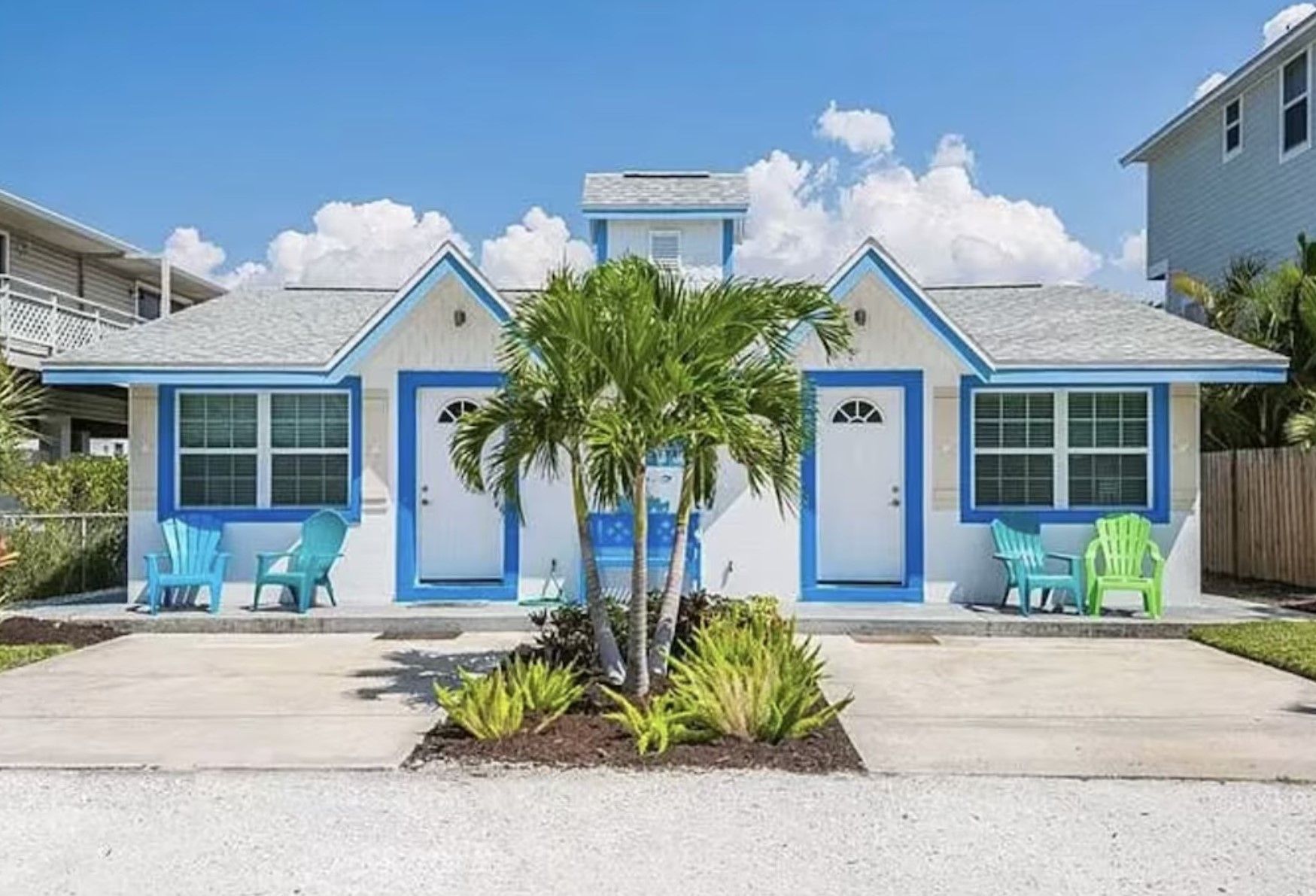 A white and blue house with a palm tree in front of it