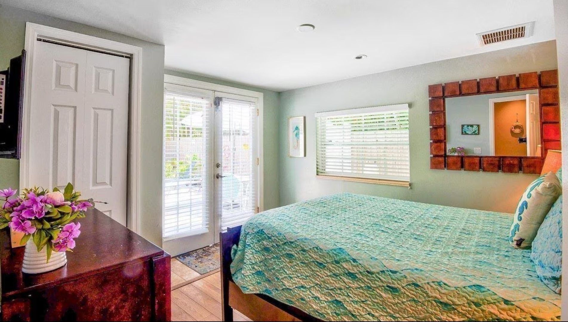 A bedroom with a bed , dresser , mirror and sliding glass doors.