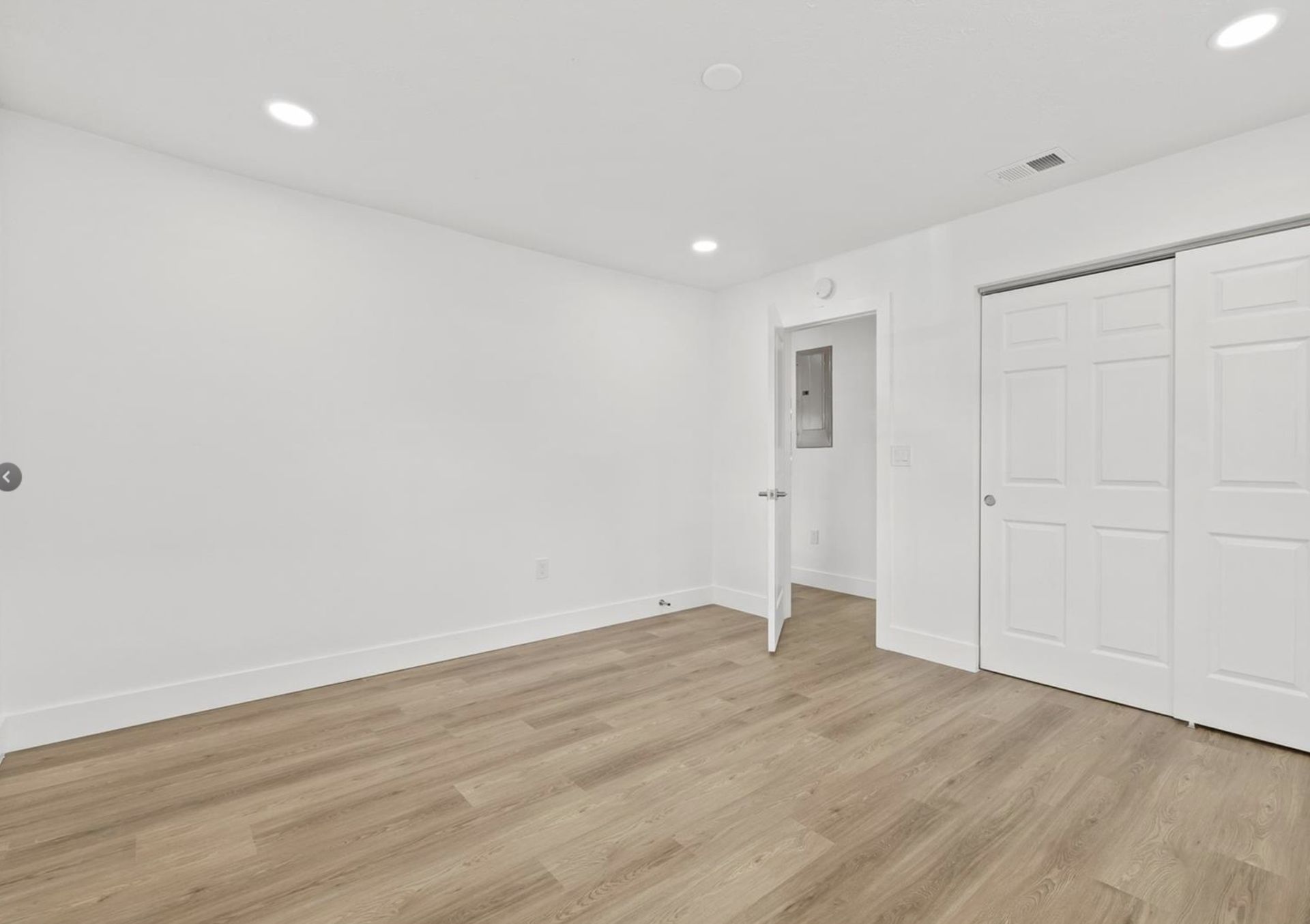 An empty room with hardwood floors and white walls.