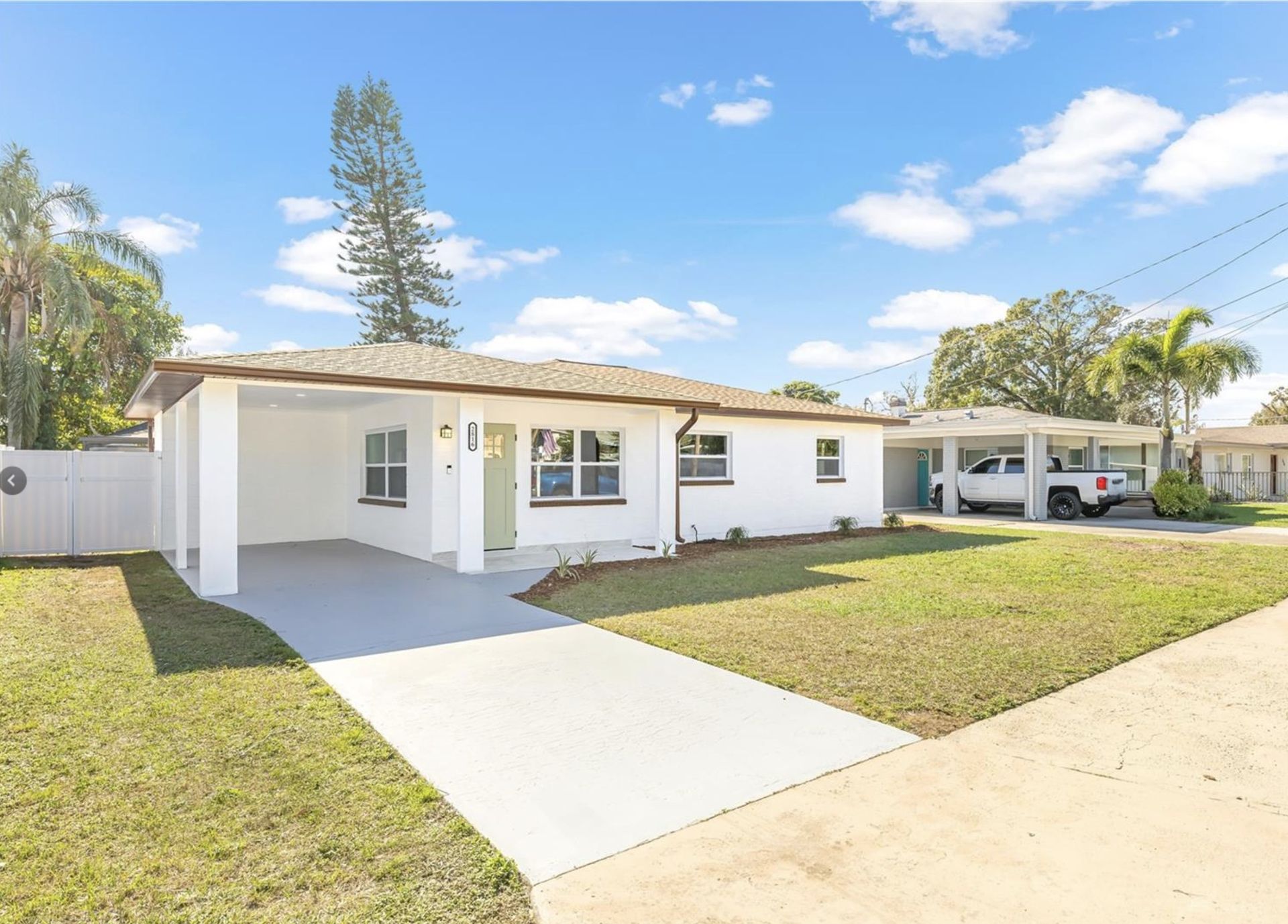 A white house with a car parked in front of it.