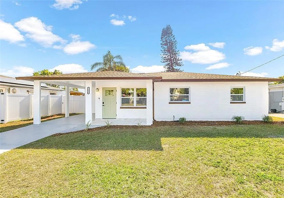 A white house with a large lawn in front of it.
