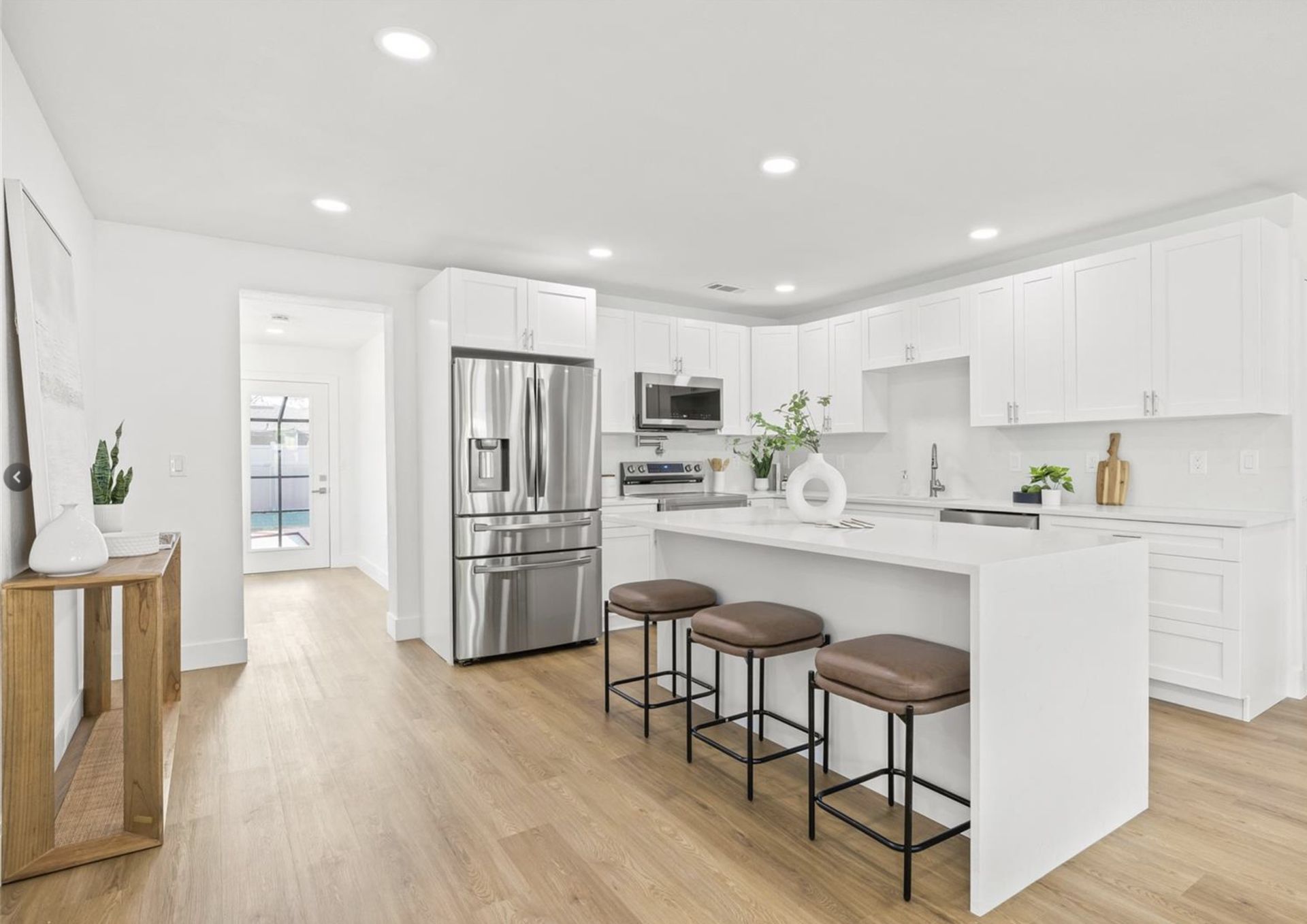 A kitchen with white cabinets , stainless steel appliances , and a large island.