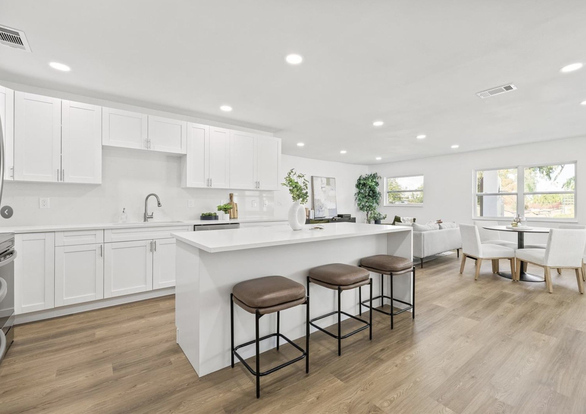 A kitchen with white cabinets and wooden floors and a large island.