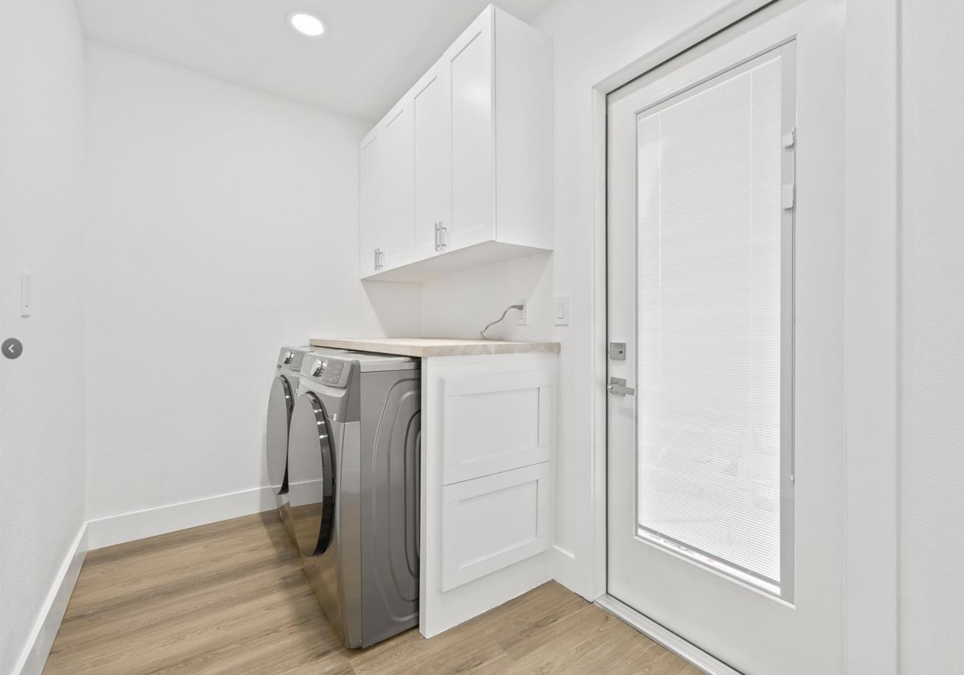 A laundry room with a washer and dryer and a door.