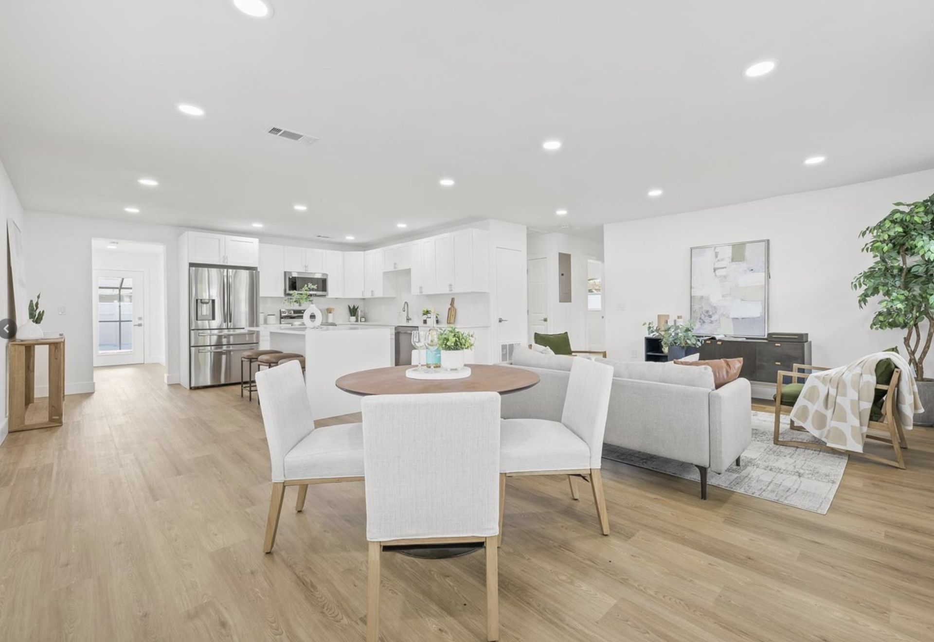 A living room with a dining table and chairs and a kitchen.