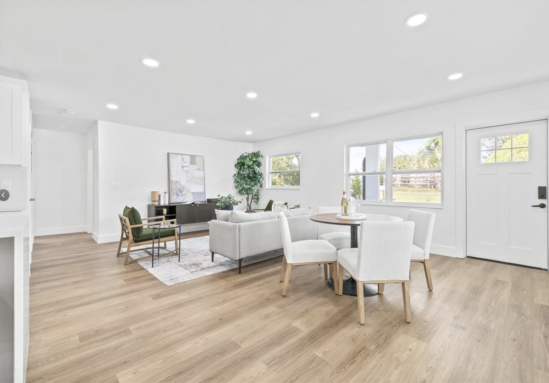 A living room and dining room in a house with hardwood floors and white furniture.