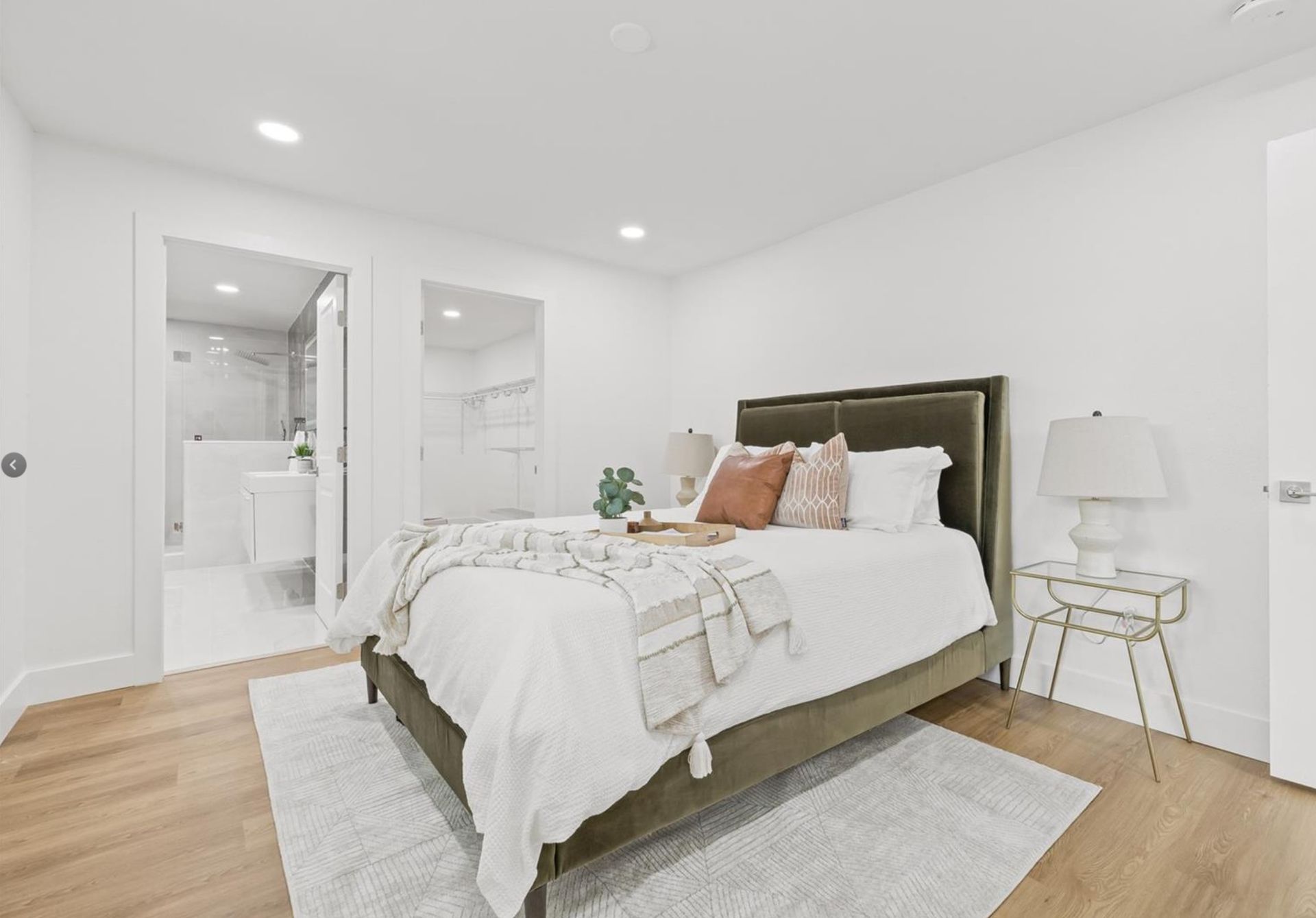 A bedroom with a bed , nightstand , lamp and rug.