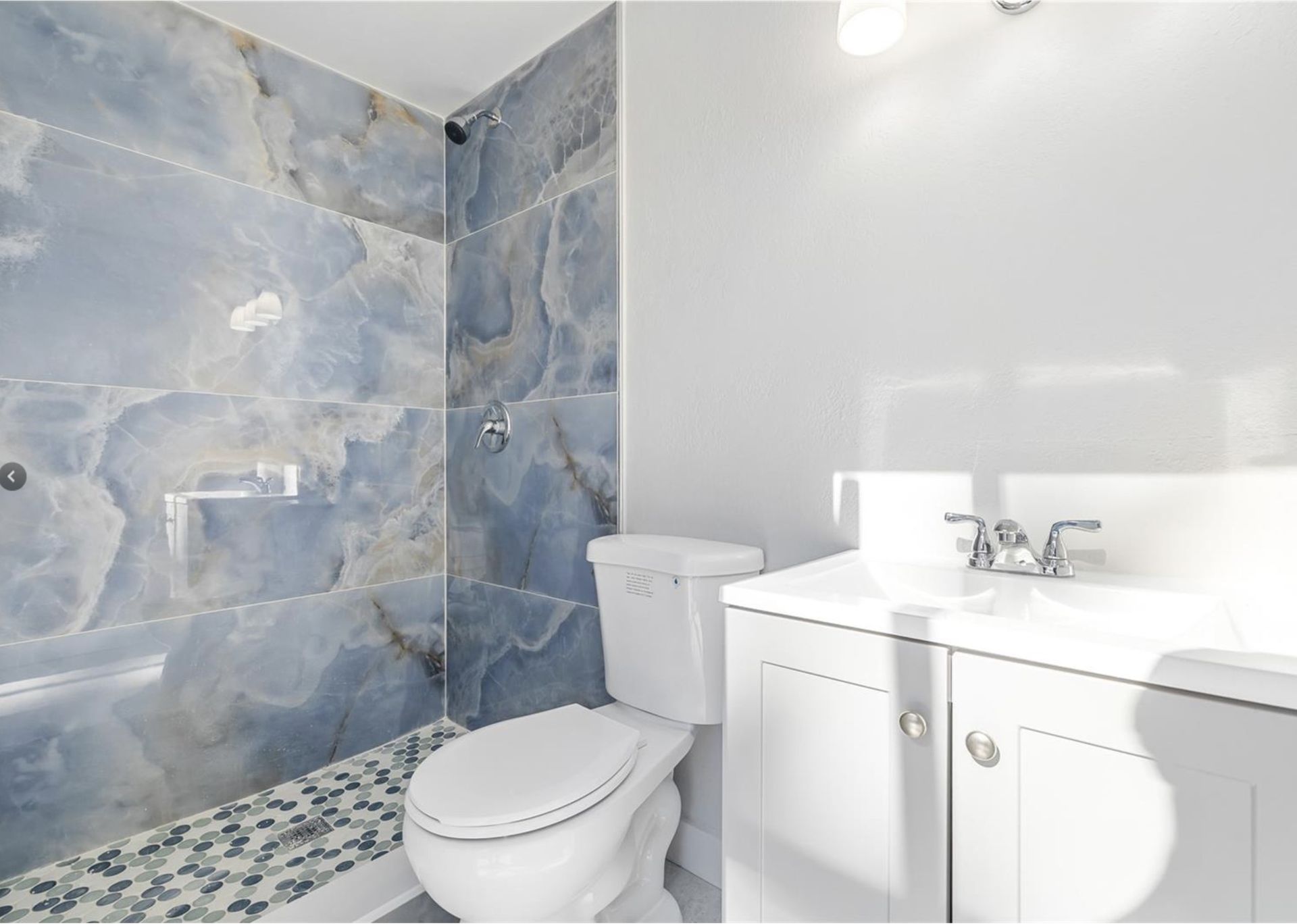 A bathroom with a toilet , sink and shower.