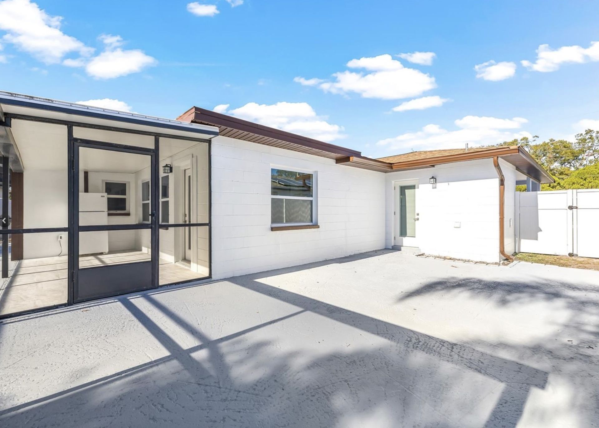 A white house with a screened in porch and a garage