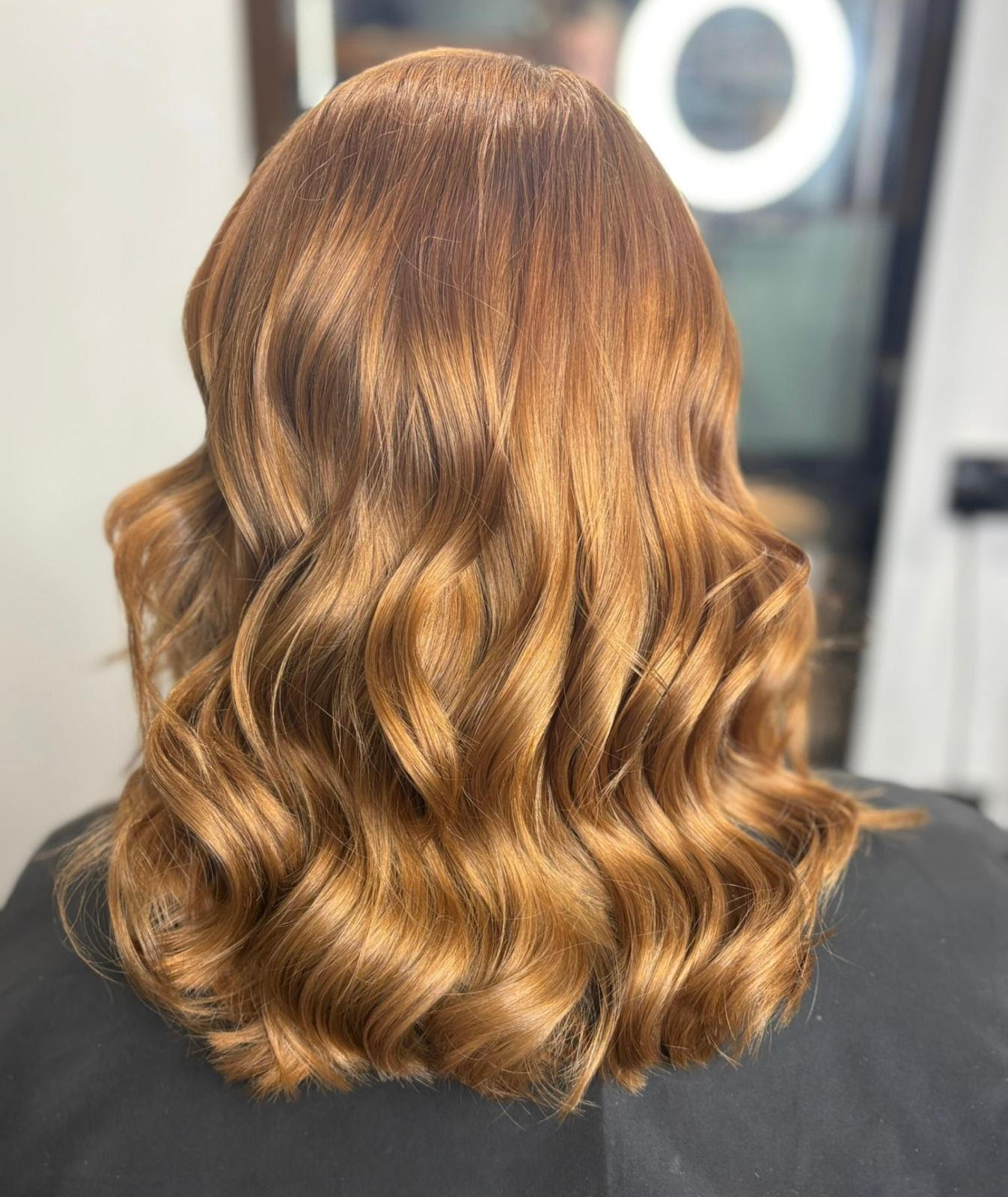 Wavy copper-brown shoulder-length hair styled in loose curls from the back