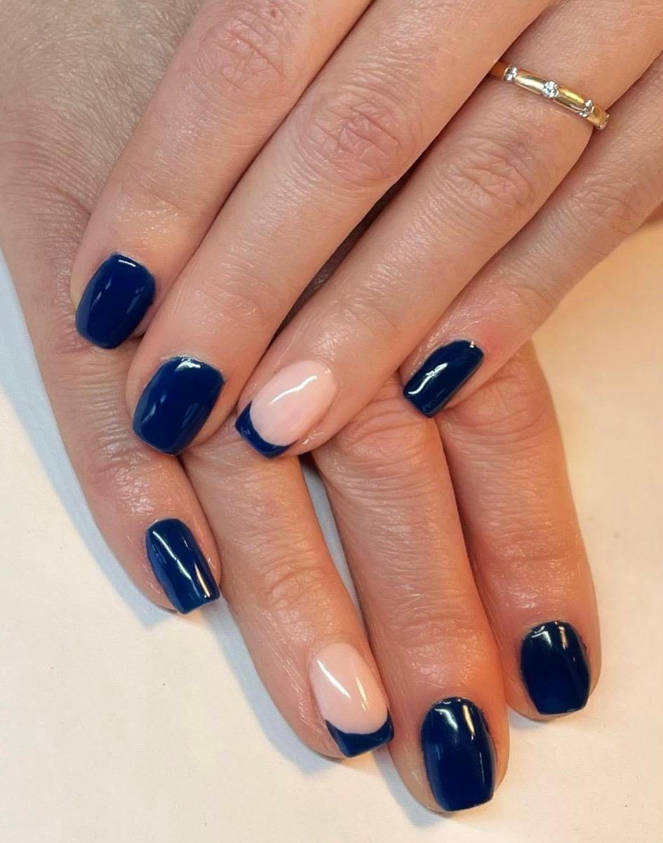 Hands with navy blue and nude manicure, overlapping against a light background.