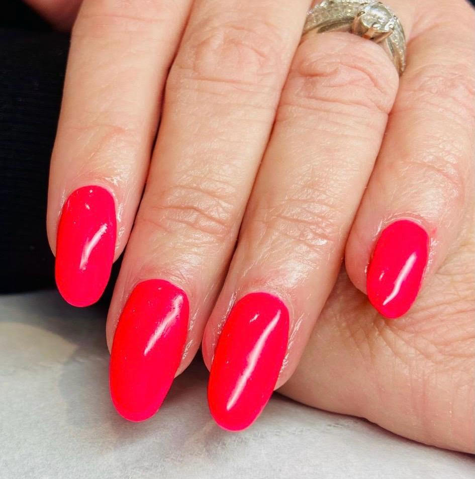Hand with bright pink manicured nails and a silver ring resting on a surface