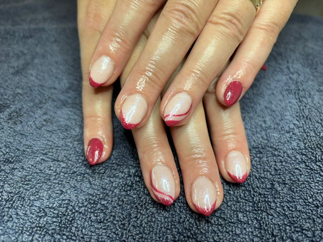 Hands with red glitter French-tip manicure resting on a dark textured surface