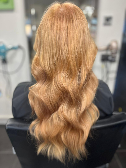 Long wavy blonde balayage hairstyle viewed from the back in a salon setting