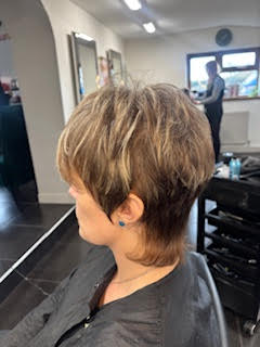 Short layered haircut with blonde highlights in a salon mirror view