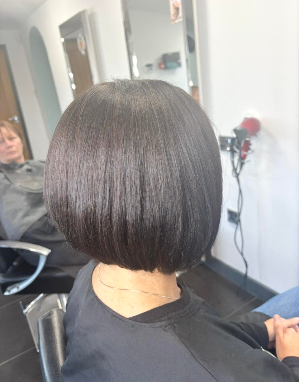 Glossy dark bob haircut seen from the back in a salon chair