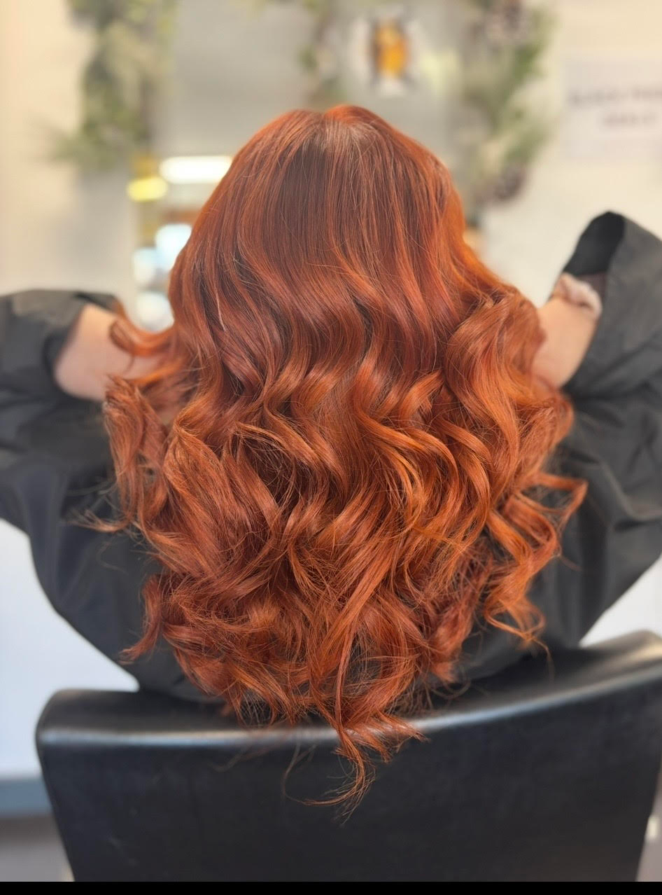 Back view of long, wavy copper-red hair in a salon chair