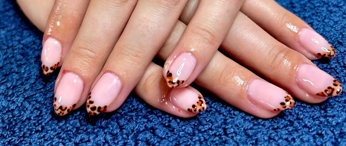 Pink manicured hands with black dotted French tips on a blue textured background