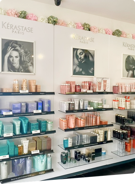 Shelves of Kérastase hair care products in a salon display with framed posters above