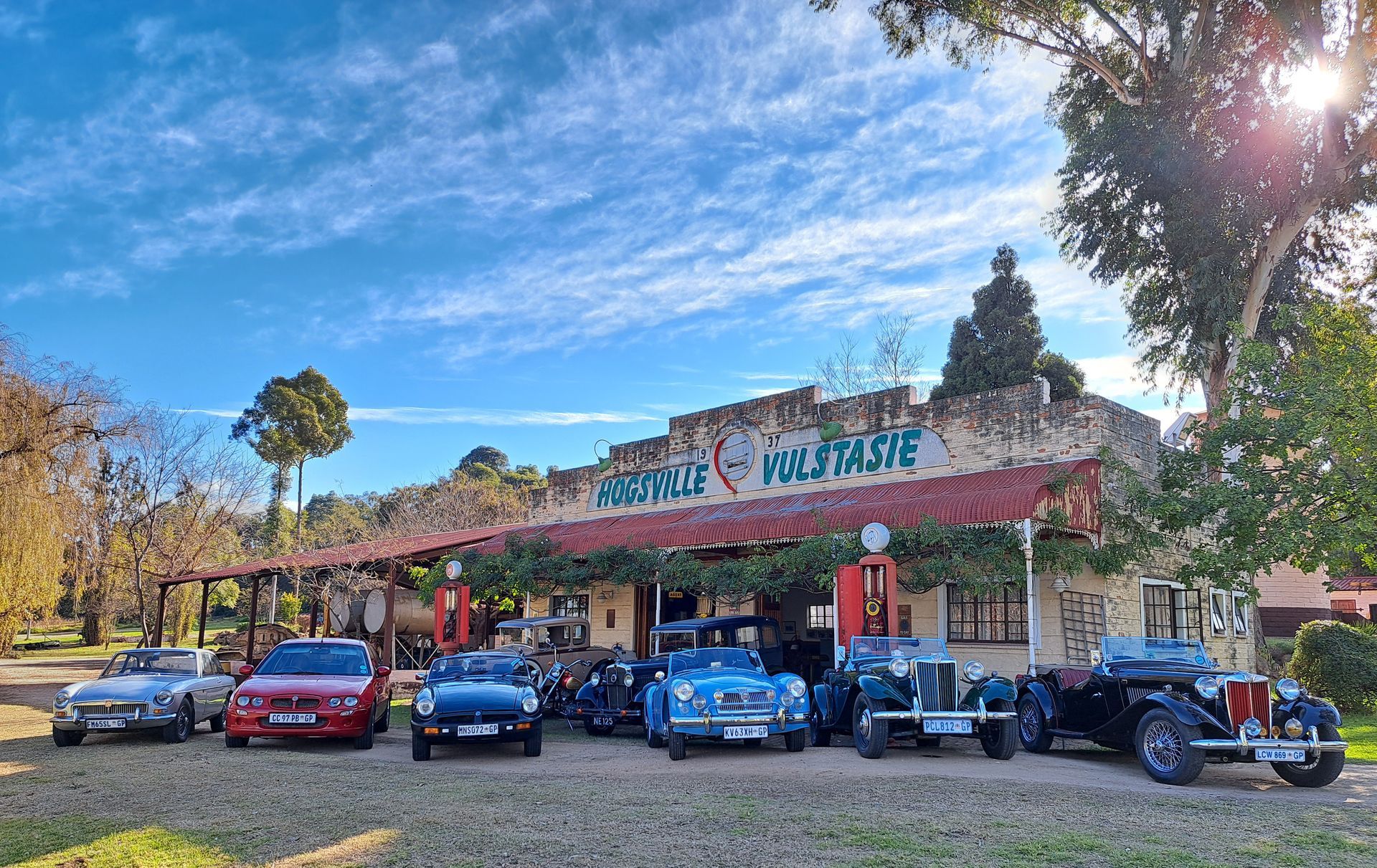 Classic cars parked in front of a stone building with 