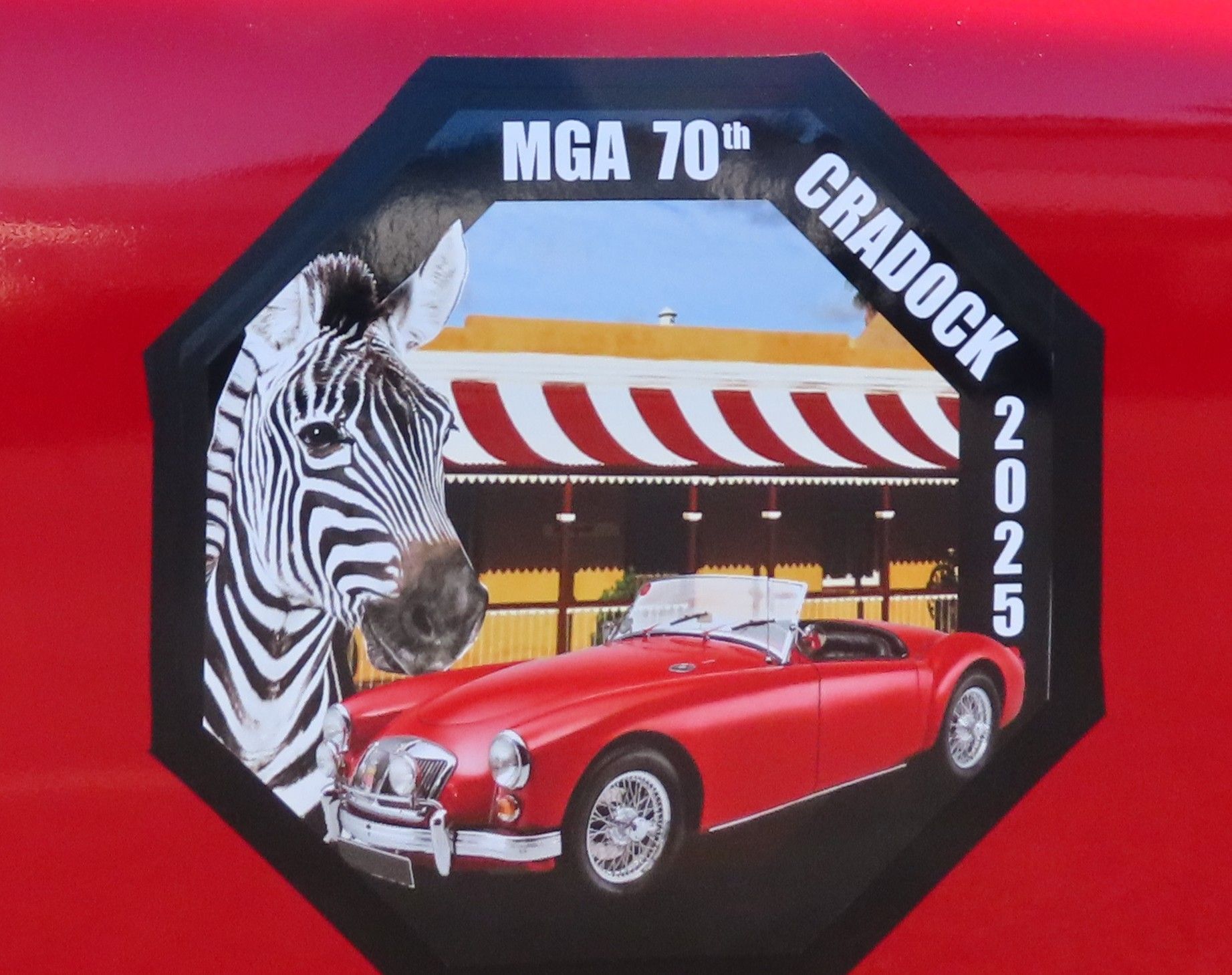 Red MGA sports car and zebra on an octagon-shaped event sticker with 