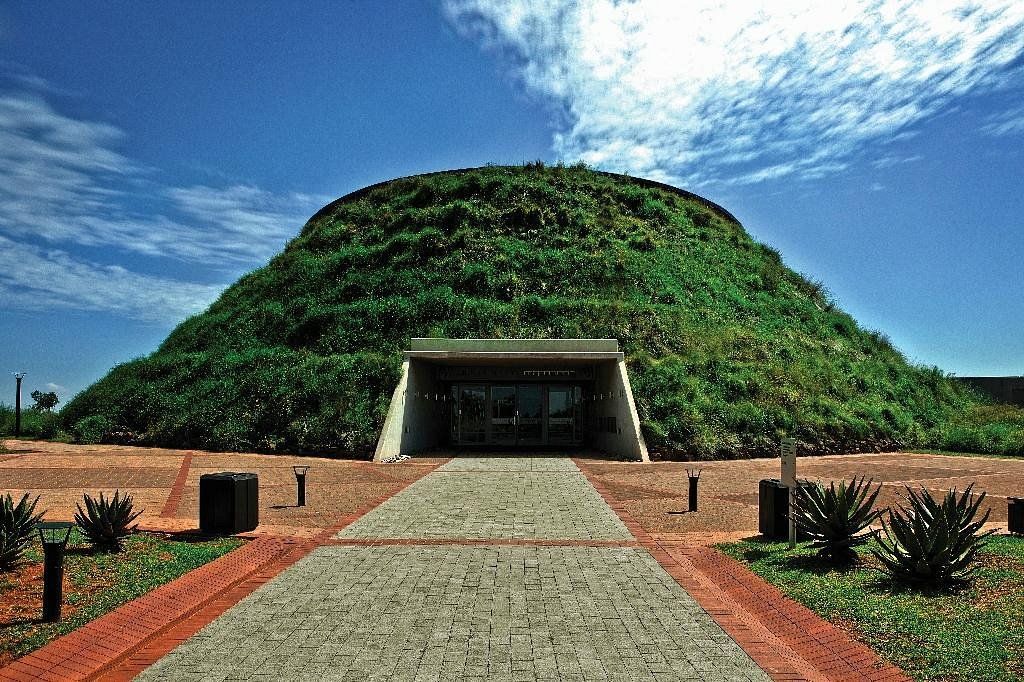 Green-covered dome building with a rectangular entrance under a blue sky.