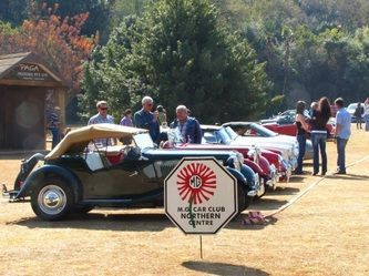 A row of old cars are parked next to a sign that says age car club northern gates