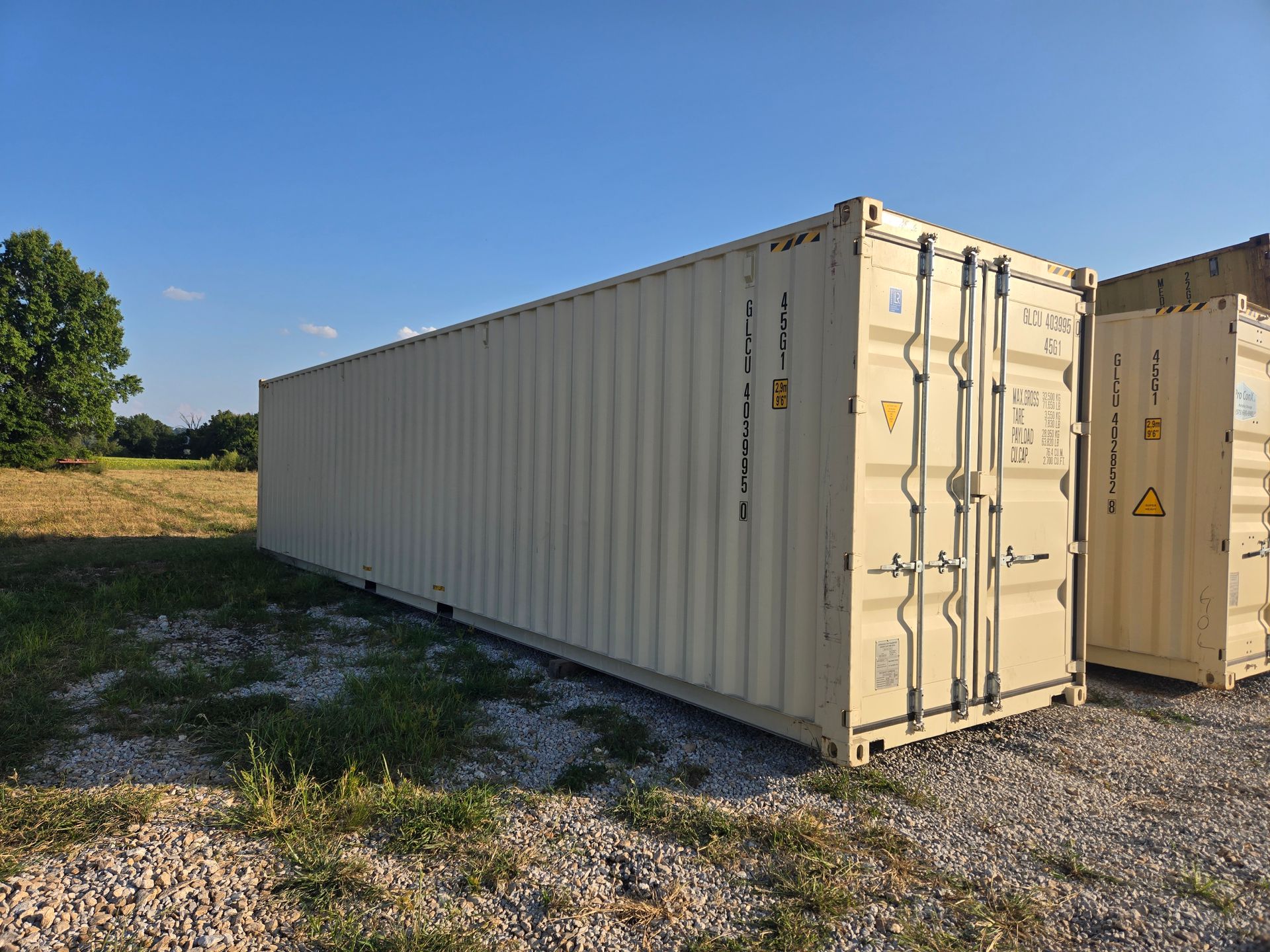 Beige shipping container in an outdoor setting under a blue sky.