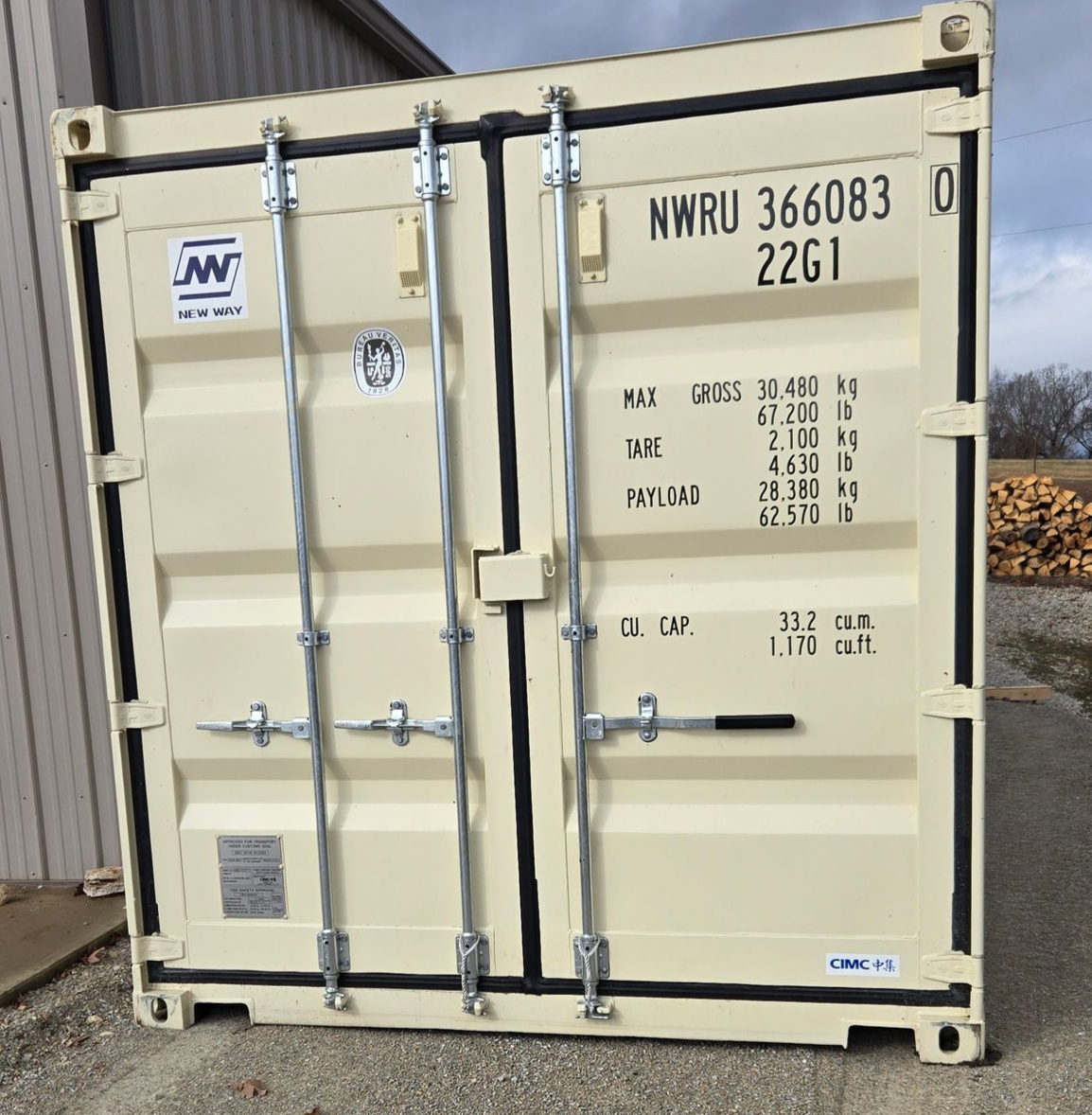 Tan shipping container, metal doors, labeled with cargo information, standing outdoors.