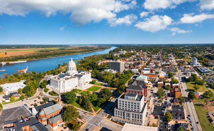 Aerial view of Jefferson City, Missouri, with the state capitol building, trees, buildings, and the Missouri River.