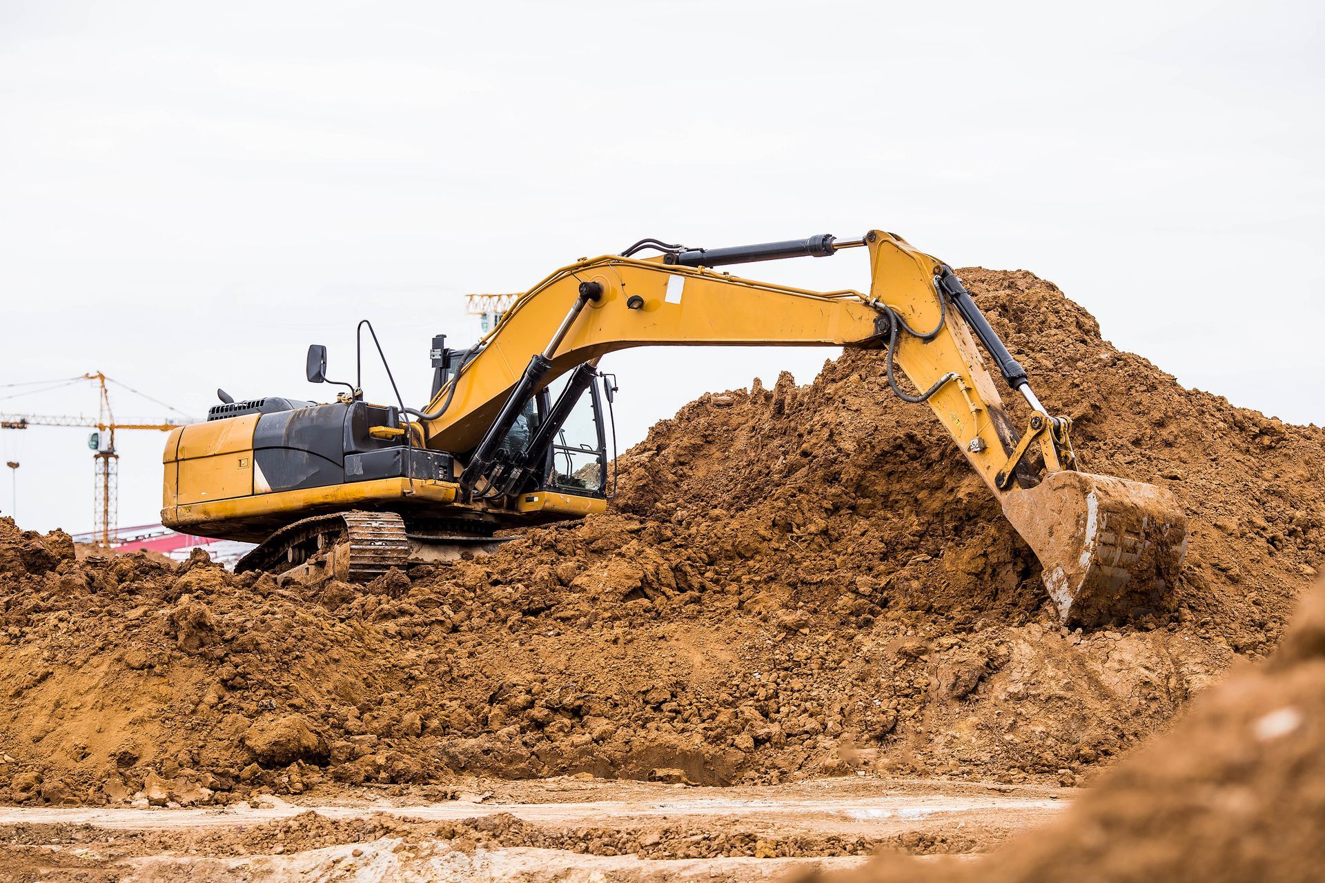 Yellow excavator in a dirt pile, scooping up soil in a construction site. Yellow excavator in a dirt pile, scooping up soil in a construction site.