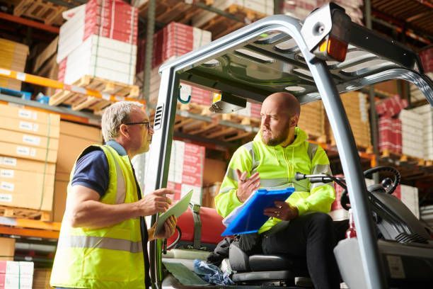 Forklift driver in warehouse showcasing heavy equipment rental, talking with supervisor on site.