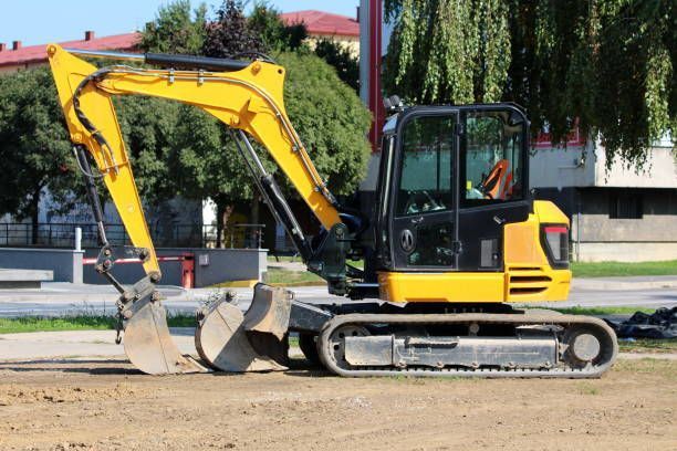 A new compact excavator was left on the side of the main road at a construction site.