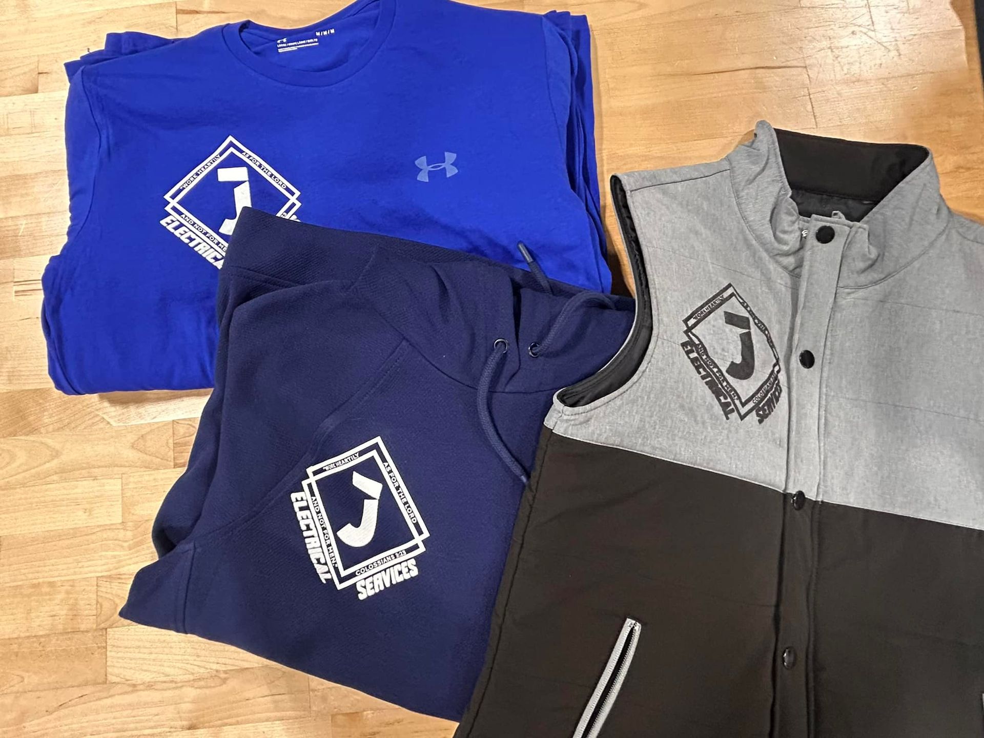 Blue and navy athletic apparel with a white logo. Grey vest with black accents.