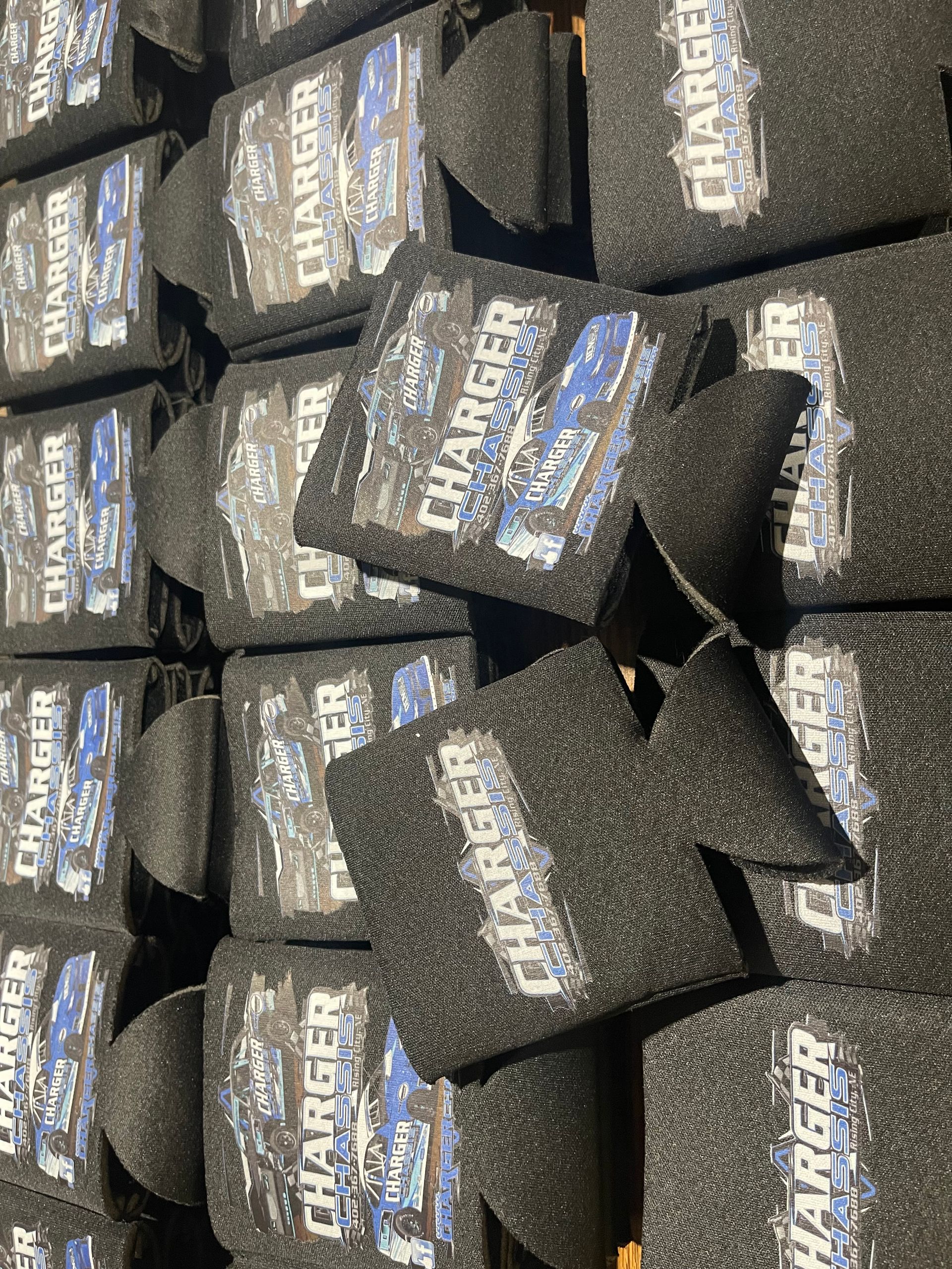 A large collection of black foam can coolers printed with a blue Dodge Charger car logo and text.
