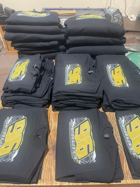 Stacks of black t-shirts featuring a large, yellow