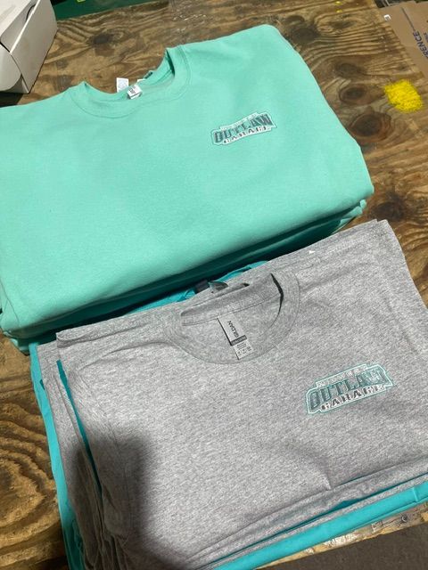 A stack of folded shirts and sweatshirts featuring a small