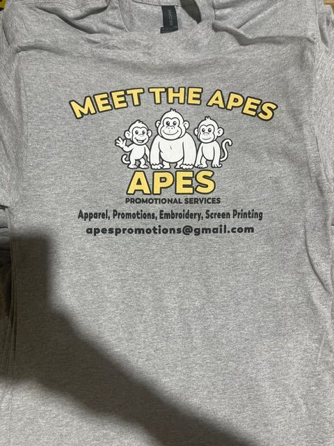 A gray t-shirt with a cartoon logo of three monkeys and the text