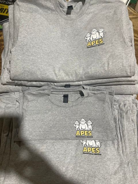 A stack of light gray t-shirts, each featuring a cartoon graphic of three apes and the word