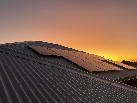 Solar panels on a rooftop with a stunning sunset backdrop. — Commercial Electrician in Port Stephens NSW