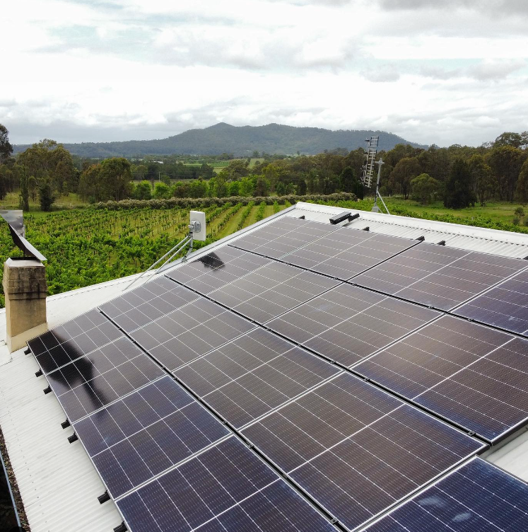 A Bunch Of Solar Panels On A Roof With Mountains In The Background — PRO Solar & Electrical In Port Stephens, NSW
