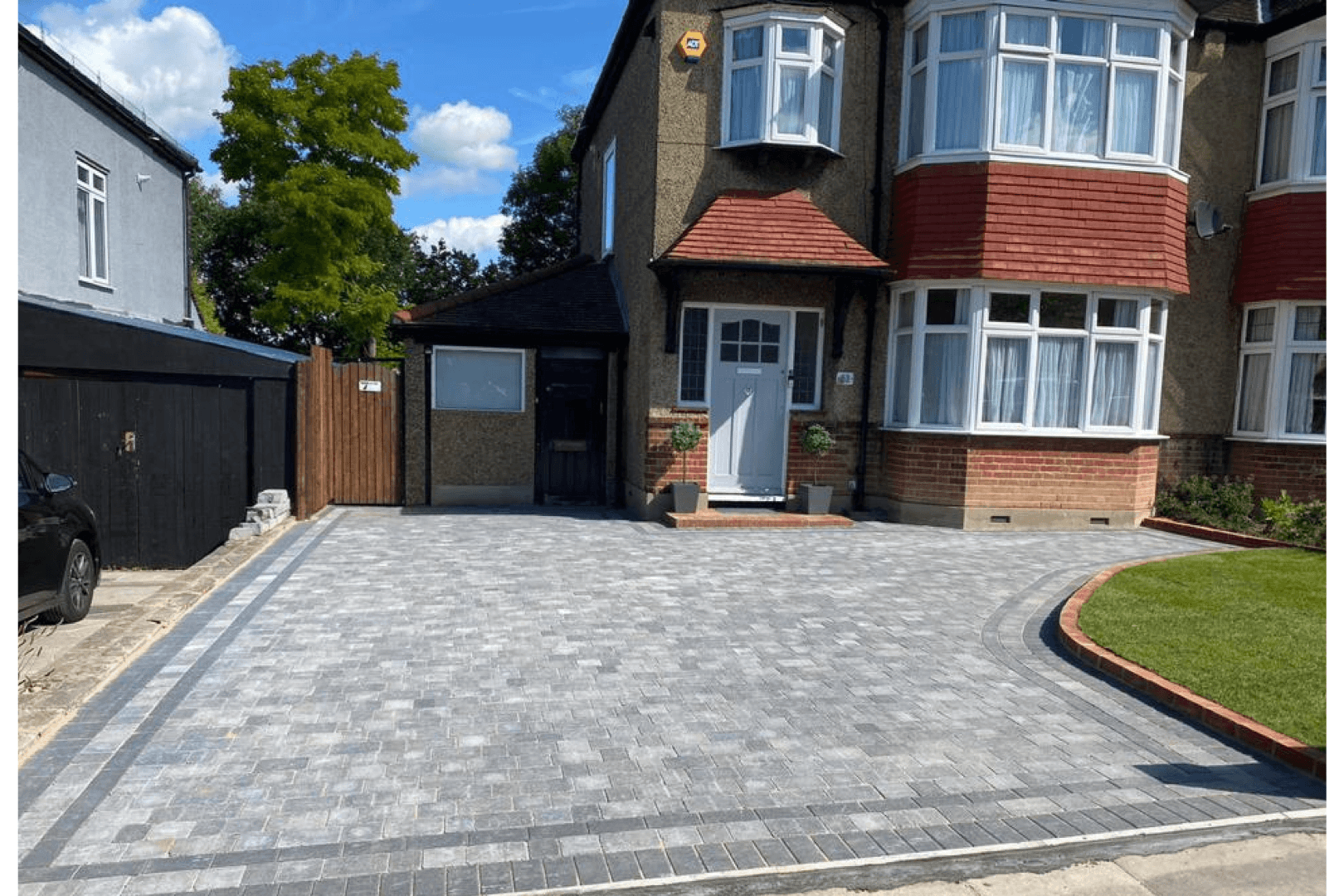 Cracked concrete driveway in front of a two-car garage. The driveway shows significant cracking, with a house and lawn in the background.