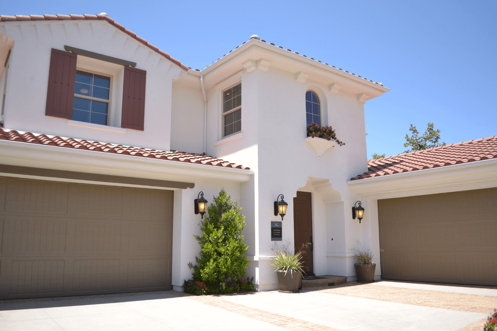 Cracked asphalt driveway in front of a two-car garage of a suburban home on a sunny day.