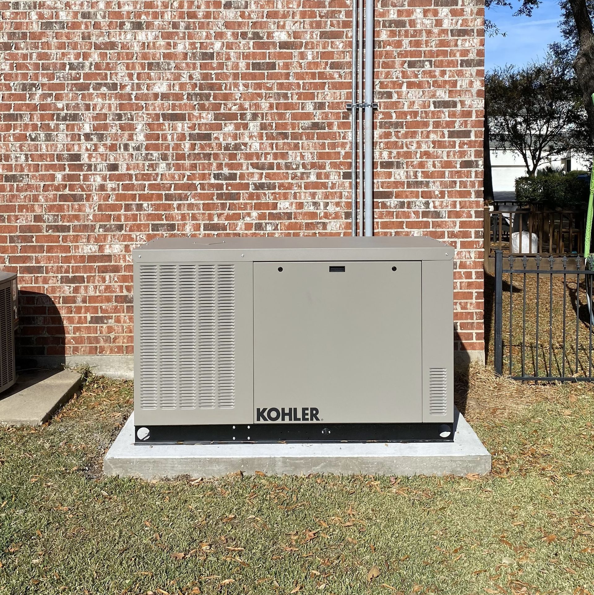 A kohler generator is sitting outside of a brick building