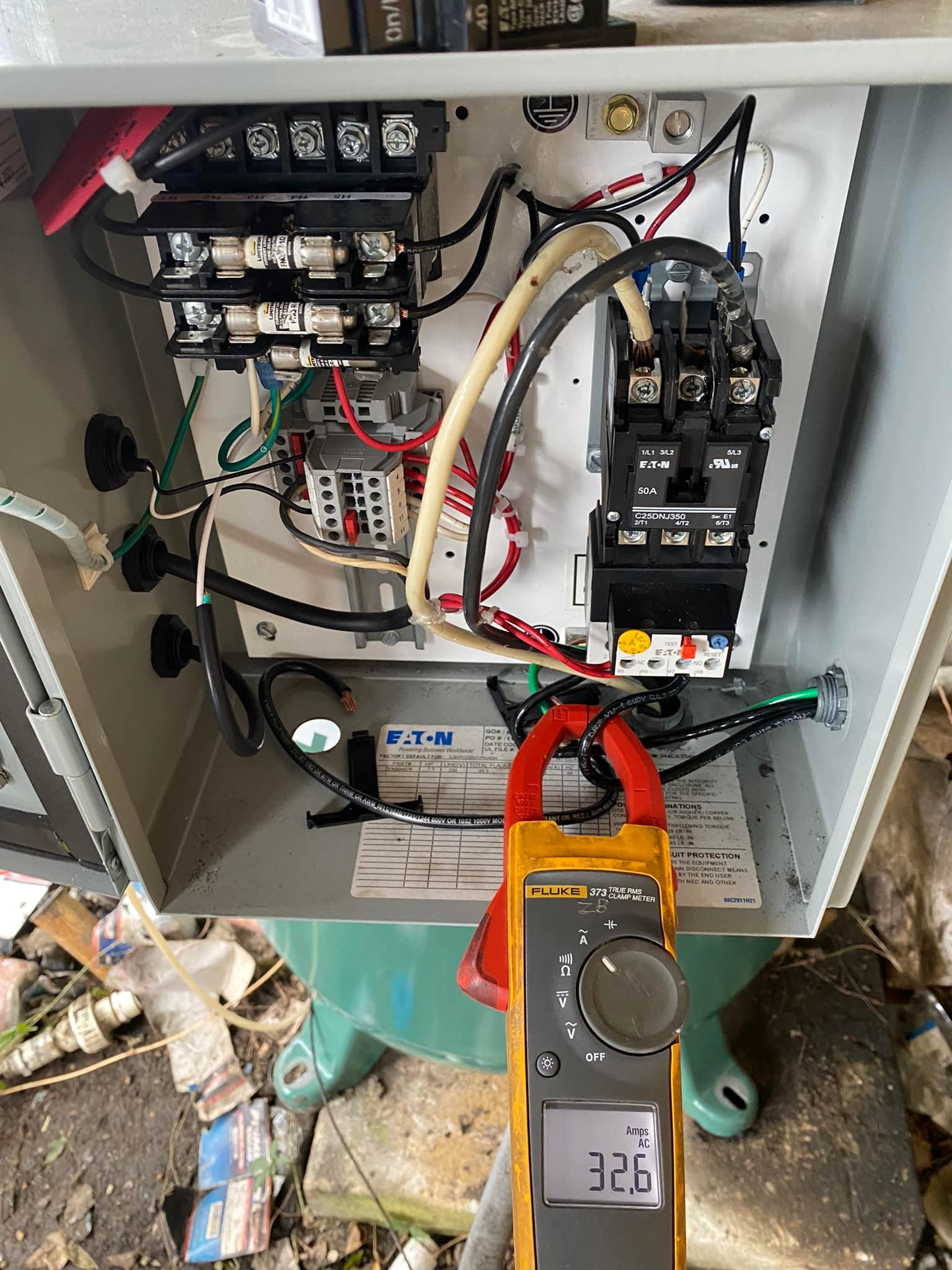A clamp meter is sitting on top of a electrical box.