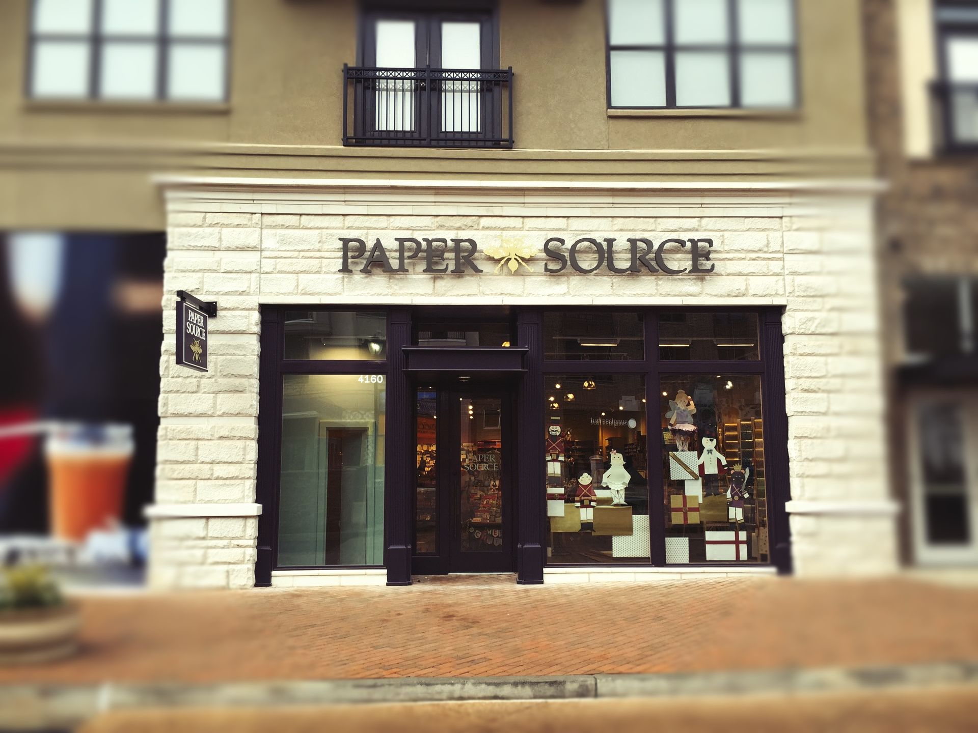 Paper Source store with large windows, sign above the door, and tan stone facade.