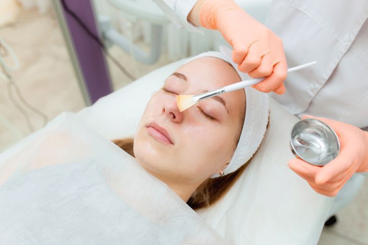 Cosmetologist applying mask on client's face