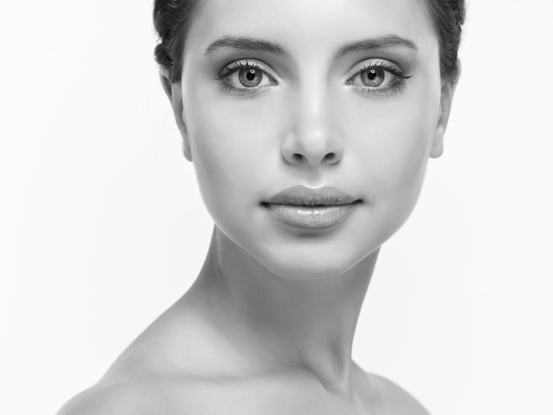 Frau mit heller Haut schaut in die Kamera, weicher Fokus, in Graustufen.