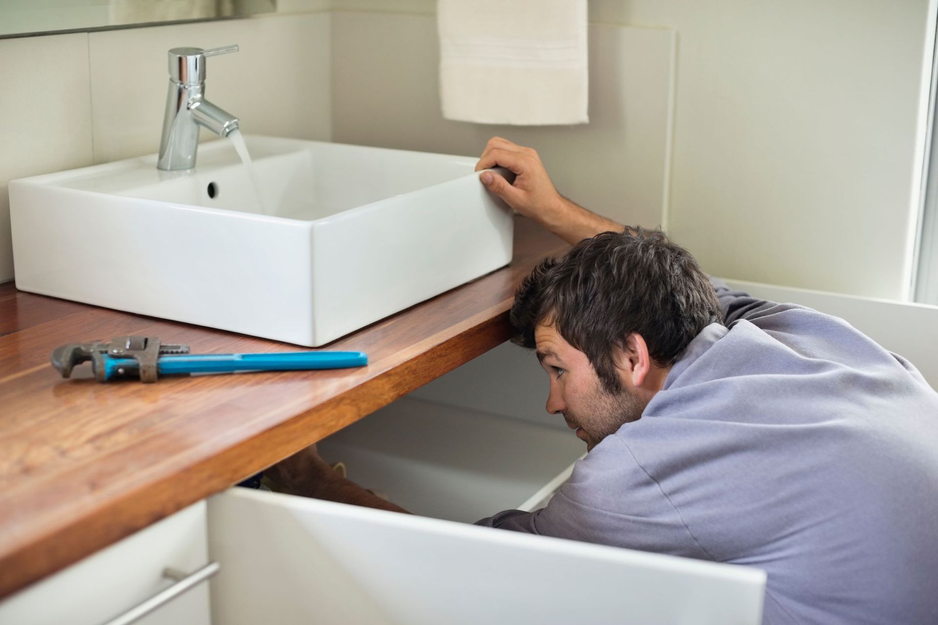 A Man Is Fixing A Sink In A Bathroom