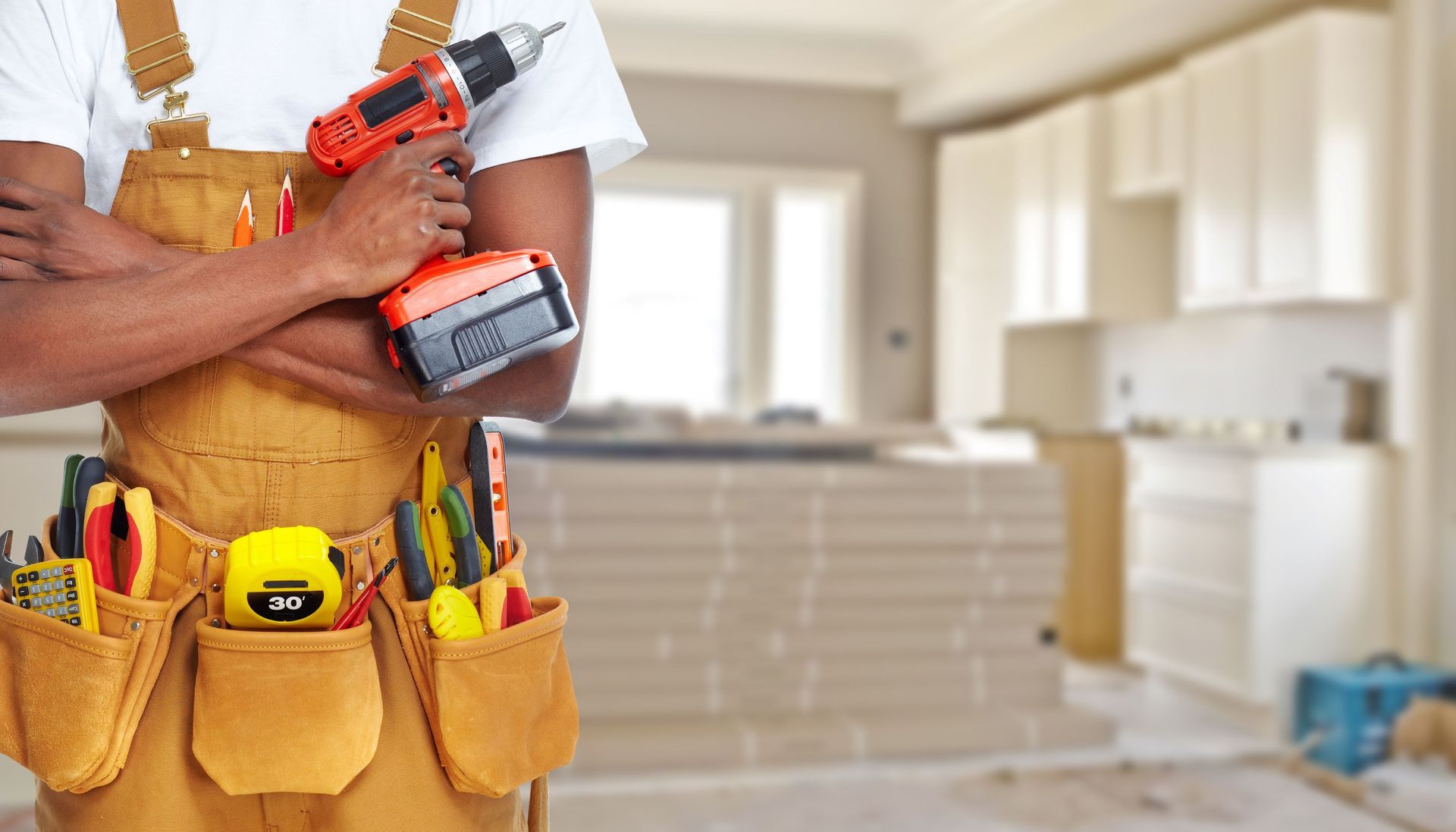A Man Is Holding A Drill In His Hand In A Kitchen